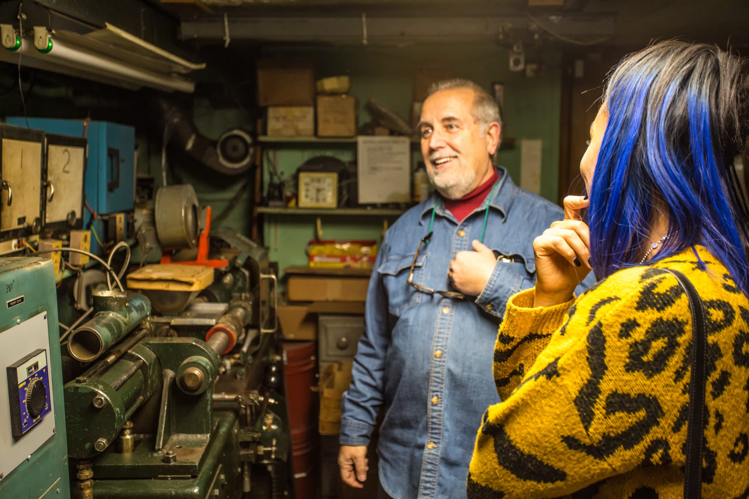 A man smiling to the side of the camera while standing in a workshop
